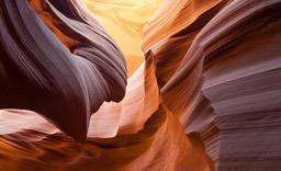 A photo of the rock texture inside Antelope Canyon, the rocks are orange and purple, with traces of natural light shining. - free wallpaper image