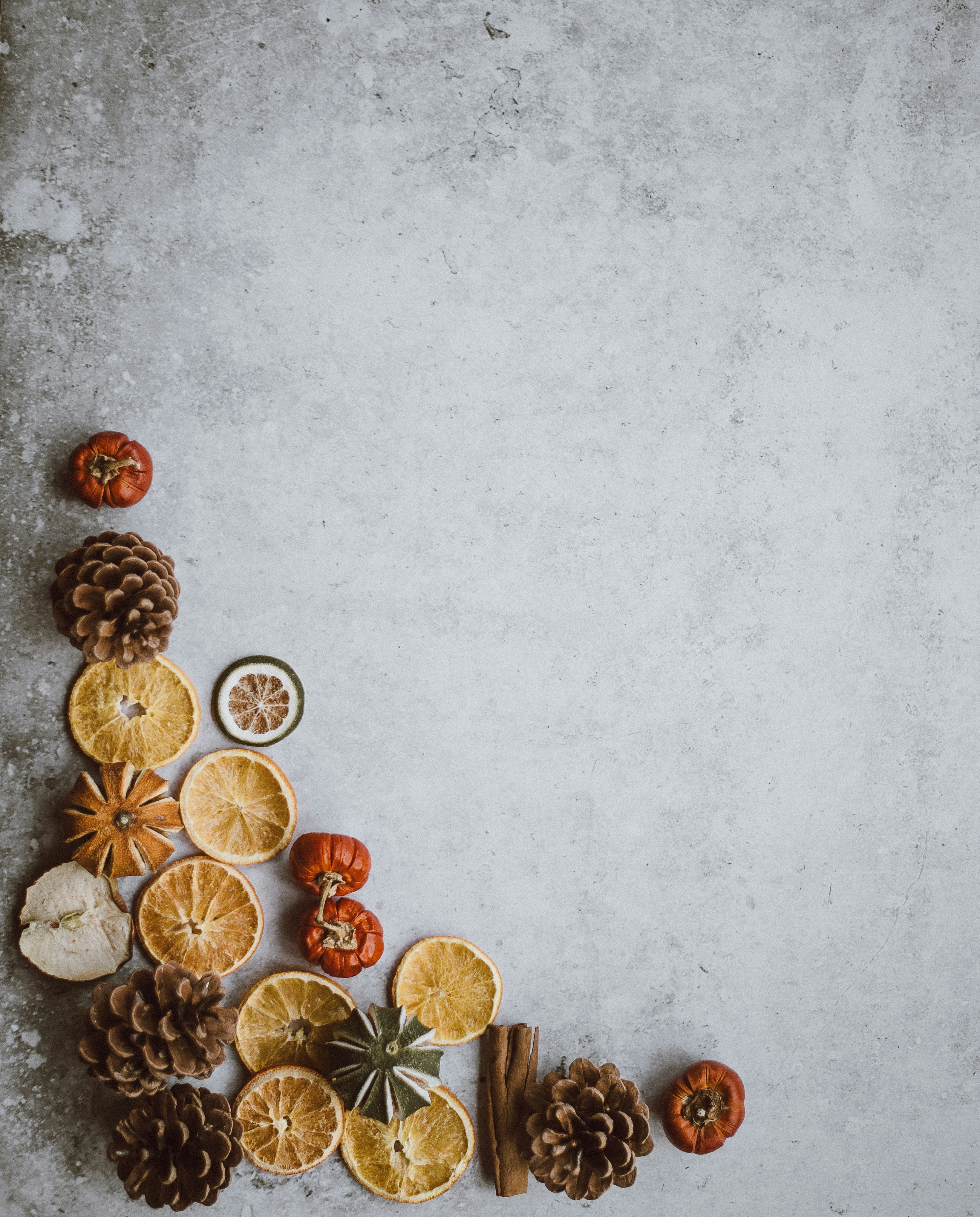 On a gray background, there are orange pumpkins, dried oranges, pine cones, cinnamon sticks and other autumn decorations. - wallpaper image