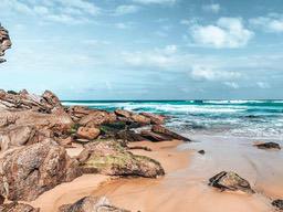 Rocks are scattered on the beach, the sea is beating the coast, the sky is blue and the clouds are floating. - free wallpaper image