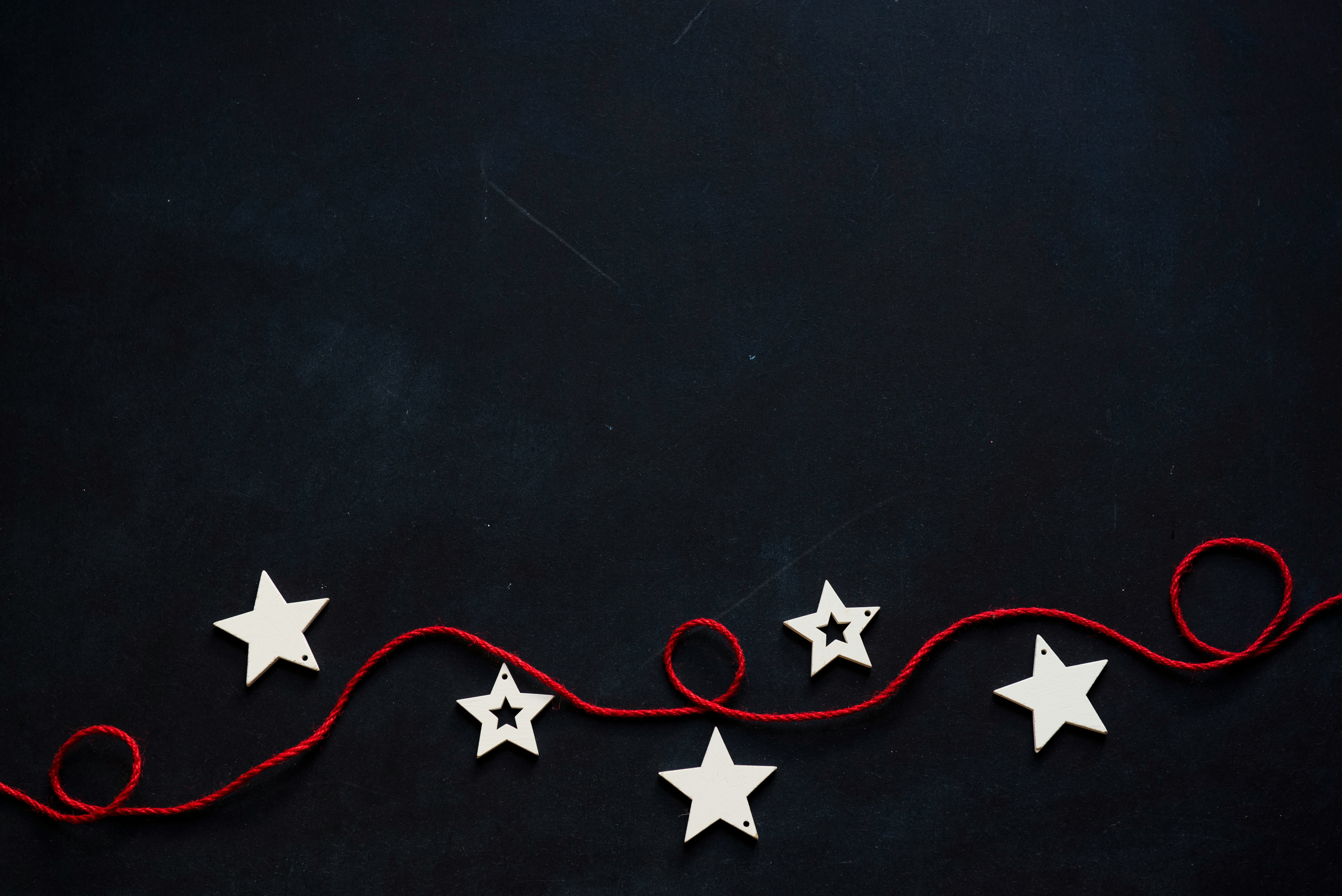 White star-shaped decorations strung together with red string on a black background. - wallpaper image