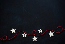 White star-shaped decorations strung together with red string on a black background. - wallpaper image