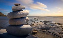 A calm sea, with white clouds in the sky, a few gray stones stacked on the shore, giving a sense of tranquility. - free wallpaper image