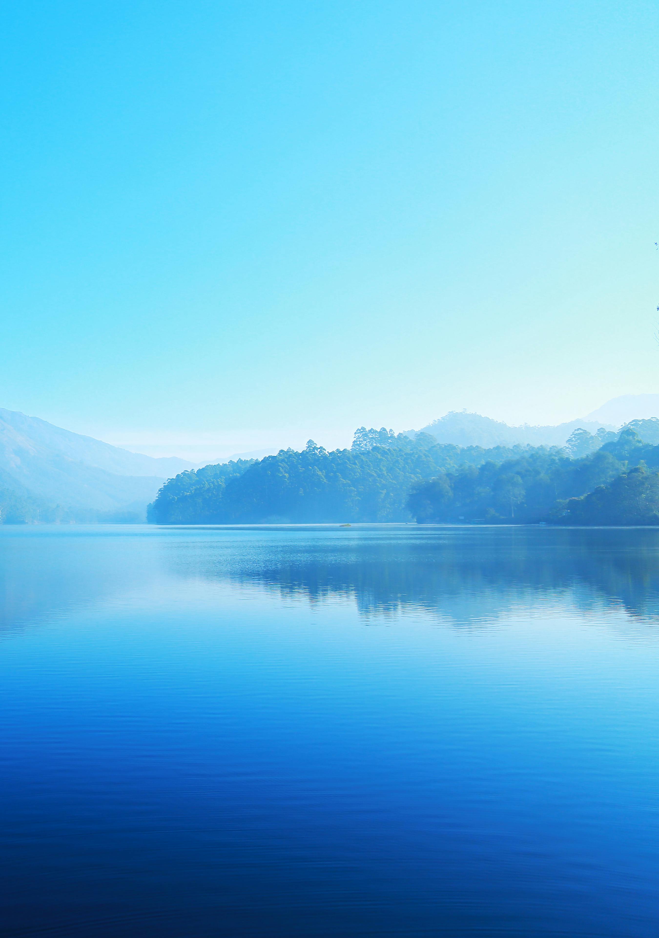 A calm lake reflects the blue sky and distant mountains, the tops of the mountains are covered with white clouds, the lake is sparkling, peaceful and beautiful. - free wallpaper image