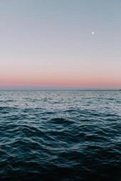 The calm sea surface is rippling, there is a crescent moon in the night sky in the distance, and the horizon is tinged with a faint pink, heralding the arrival of dawn. - free wallpaper image