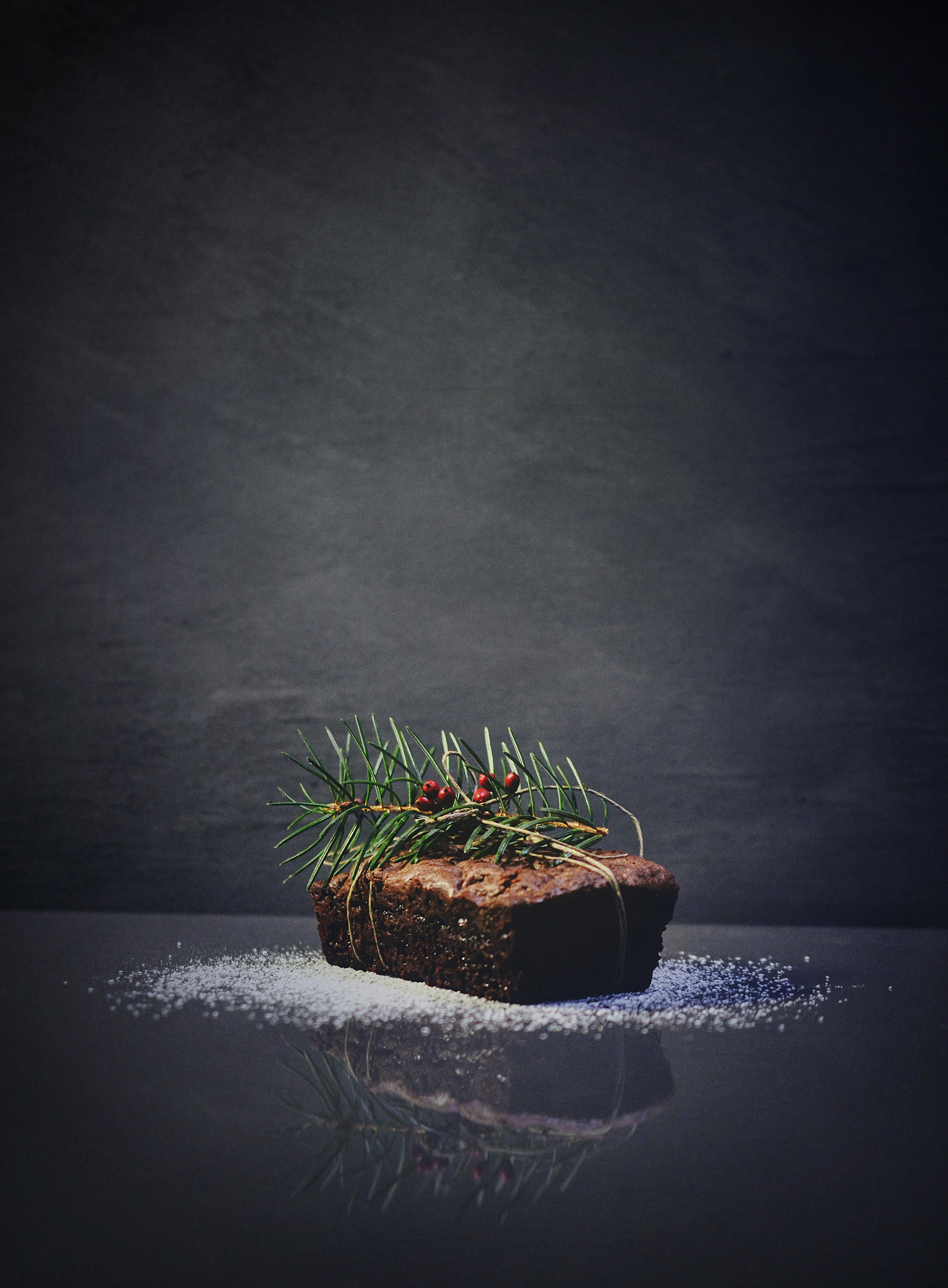 A chocolate cake tied with twine and decorated with a Christmas tree branch and red berries. - wallpaper image