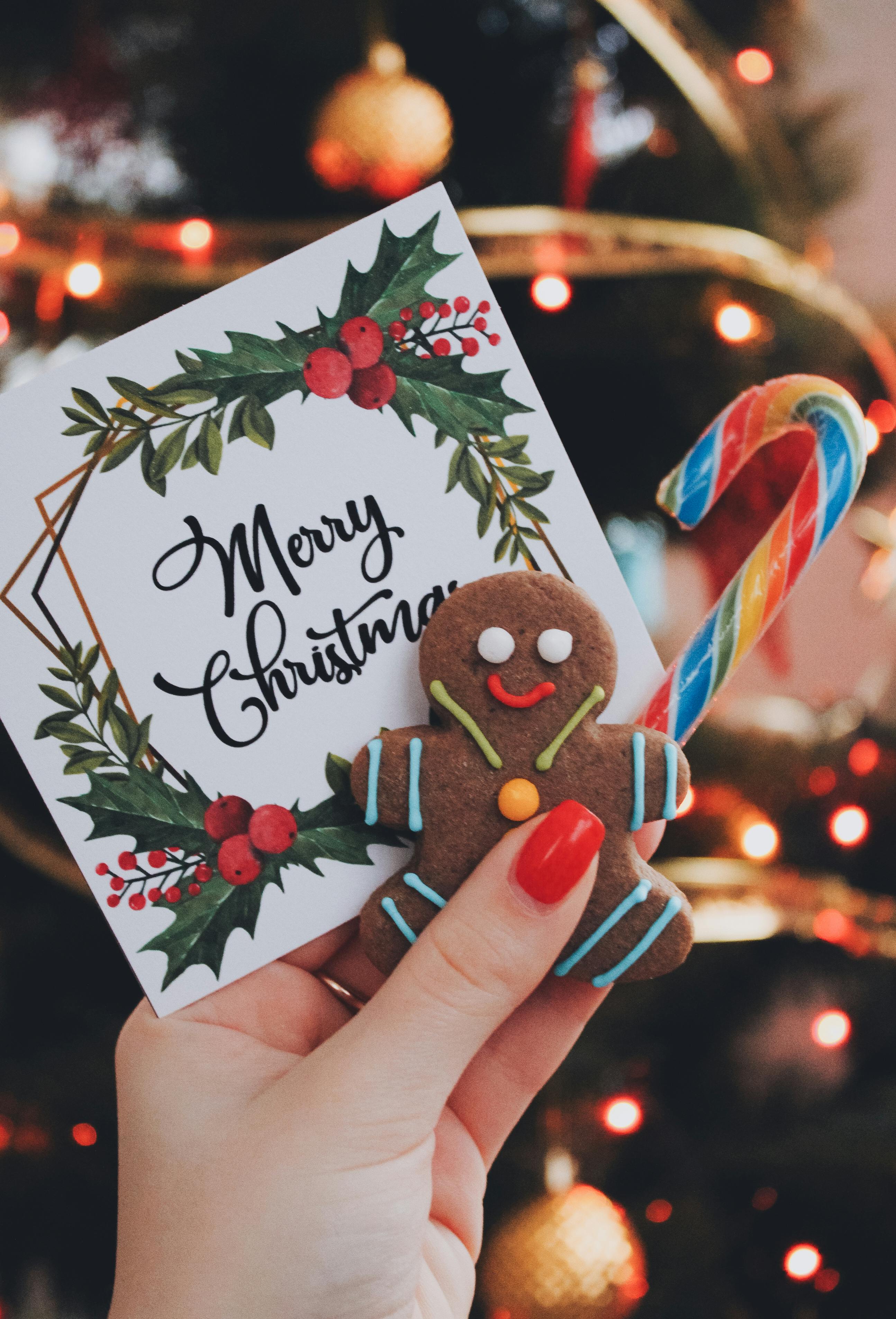 A Christmas card with the words “Merry Christmas” on it, next to a gingerbread man and a colorful candy cane. - wallpaper image