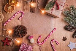 A flat lay photo on a wooden background with Christmas decorations such as candy canes, pine cones, stars, gift boxes, etc., creating a warm festive atmosphere. - wallpaper image