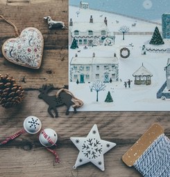 A wooden table with a Christmas advent calendar, a decorative heart, a decorative deer, two decorative bells, a decorative star and a roll of twine. - wallpaper image