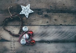 Some Christmas decorations are placed on a wooden background, including a heart-shaped decoration, a star, a few bells and red berries - wallpaper image