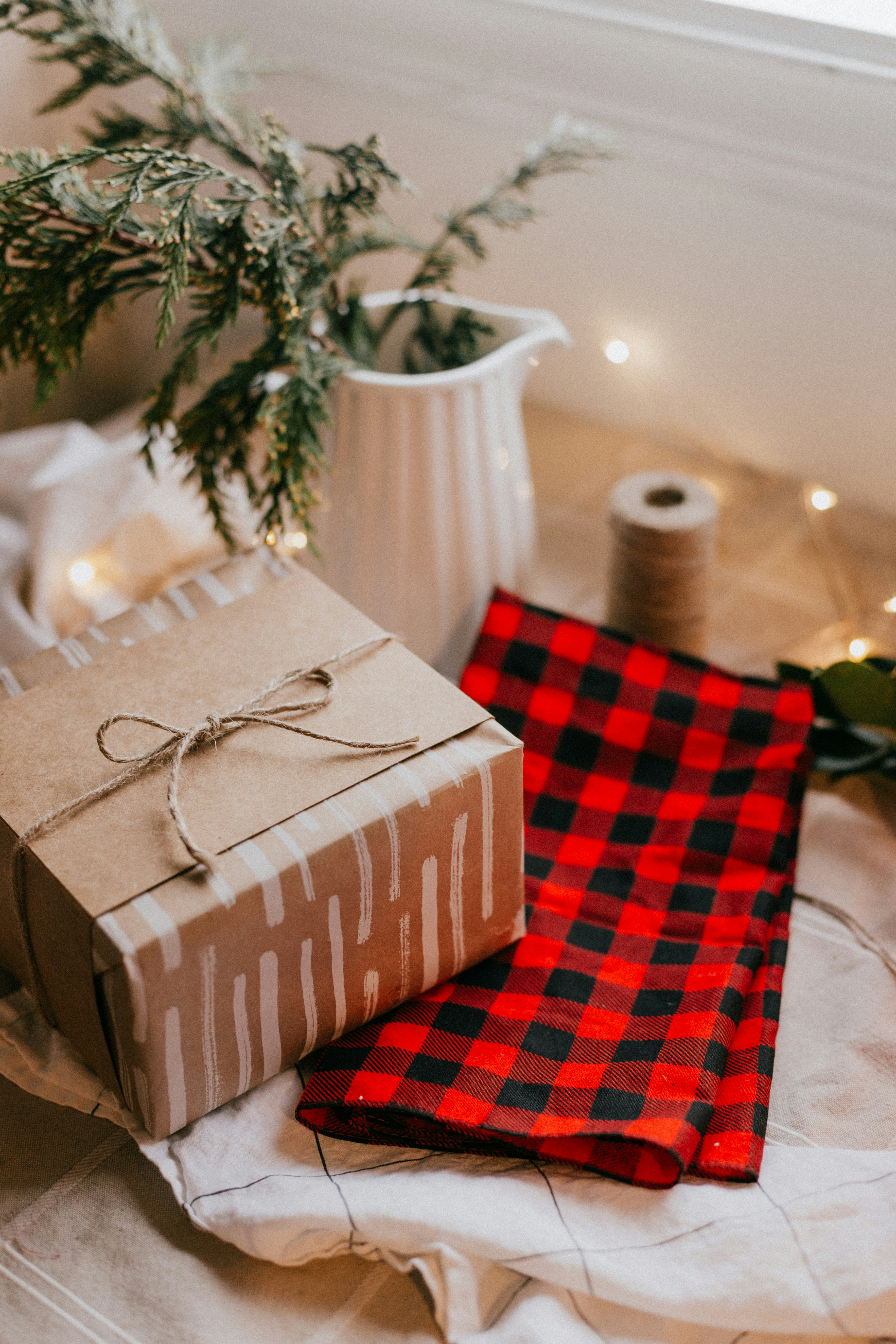 A wrapped gift box is placed on a red and black checkered fabric, with some decorations beside it. - wallpaper image