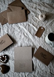 Some envelopes, cards, candies, yarn and a ceramic cup are placed on a white cloth, the overall color tone is warm and simple, creating a warm and comfortable atmosphere. - wallpaper image