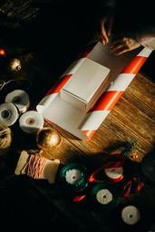 A wooden table with a wrapped gift box and wrapping supplies, such as ribbons and ropes. The scene creates a warm and comfortable atmosphere. - wallpaper image