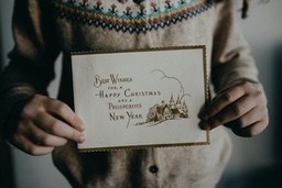 A young girl in a sweater is holding a Christmas card that says &apos;Best wishes for a Happy Christmas and a Prosperous New Year&apos;. - wallpaper image