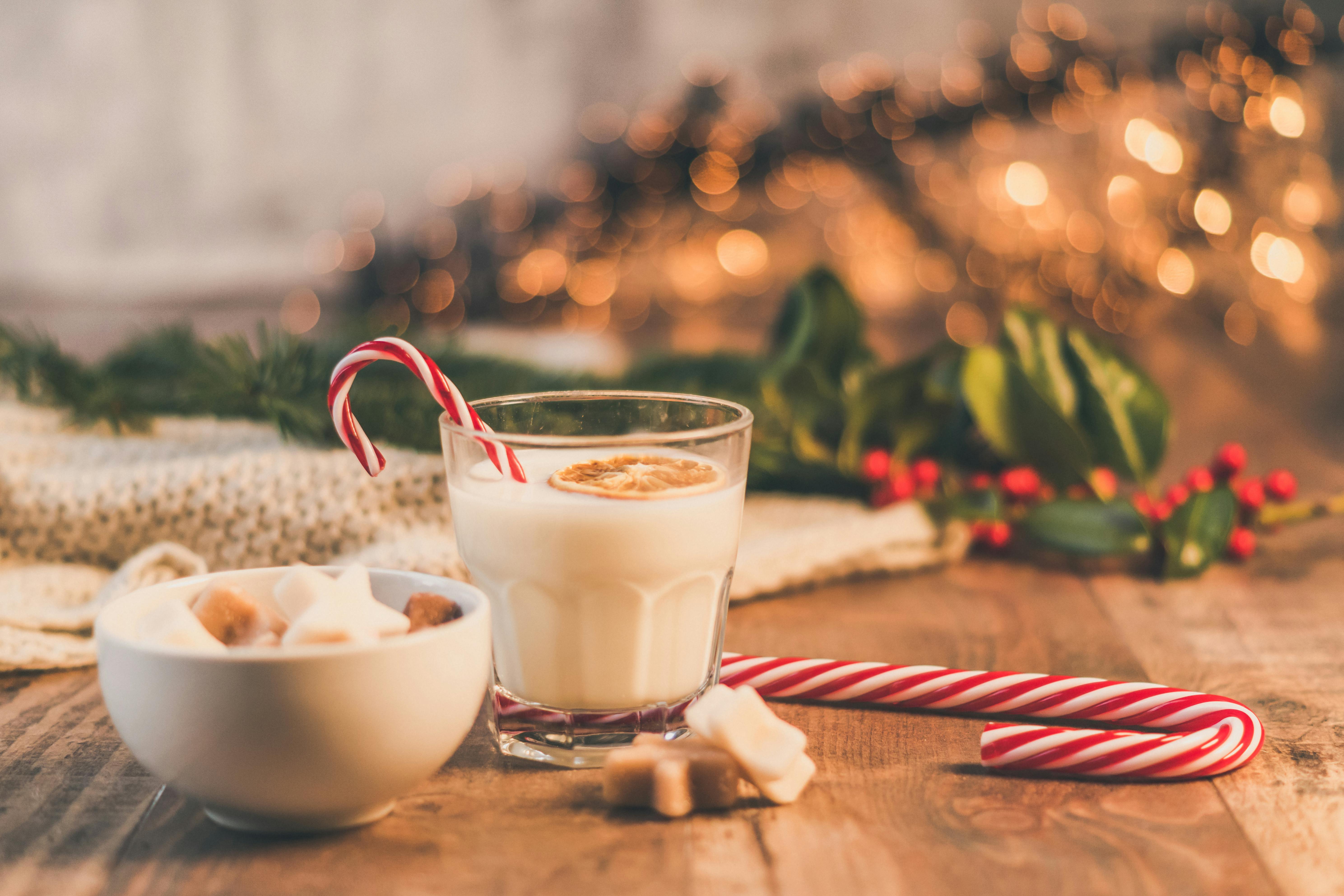 A glass of hot milk with candy canes and cookies, looks especially warm under the warm lights. - wallpaper image