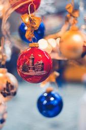 Several Christmas ornaments hang on the branches of a tree, one of which has a castle pattern printed on it. - wallpaper image