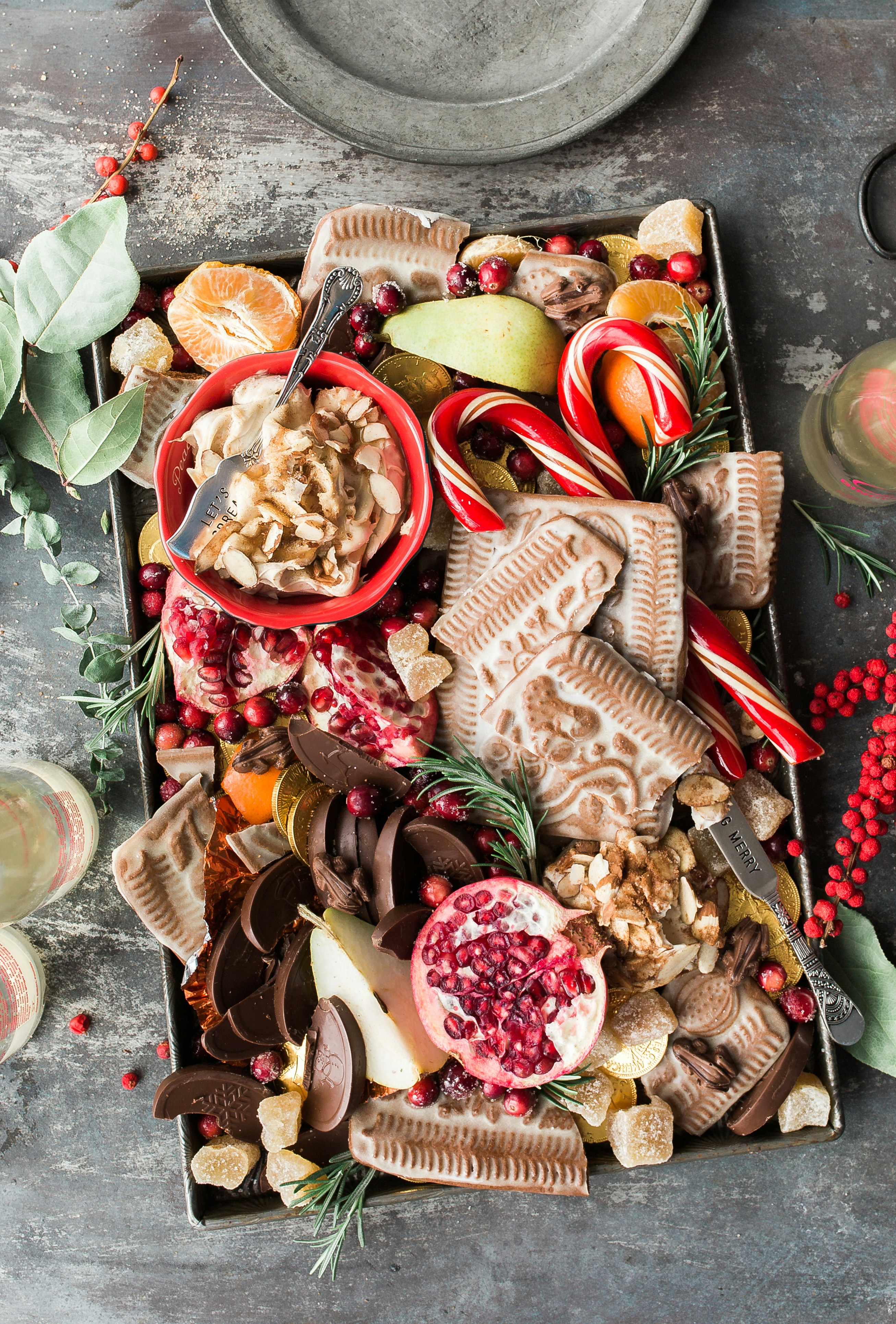 A tray filled with a variety of Christmas snacks, including chocolate, candies, fruits and nuts. - wallpaper image