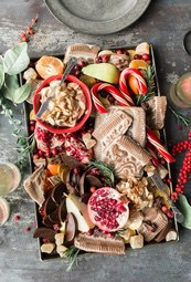 A tray filled with a variety of Christmas snacks, including chocolate, candies, fruits and nuts. - wallpaper image