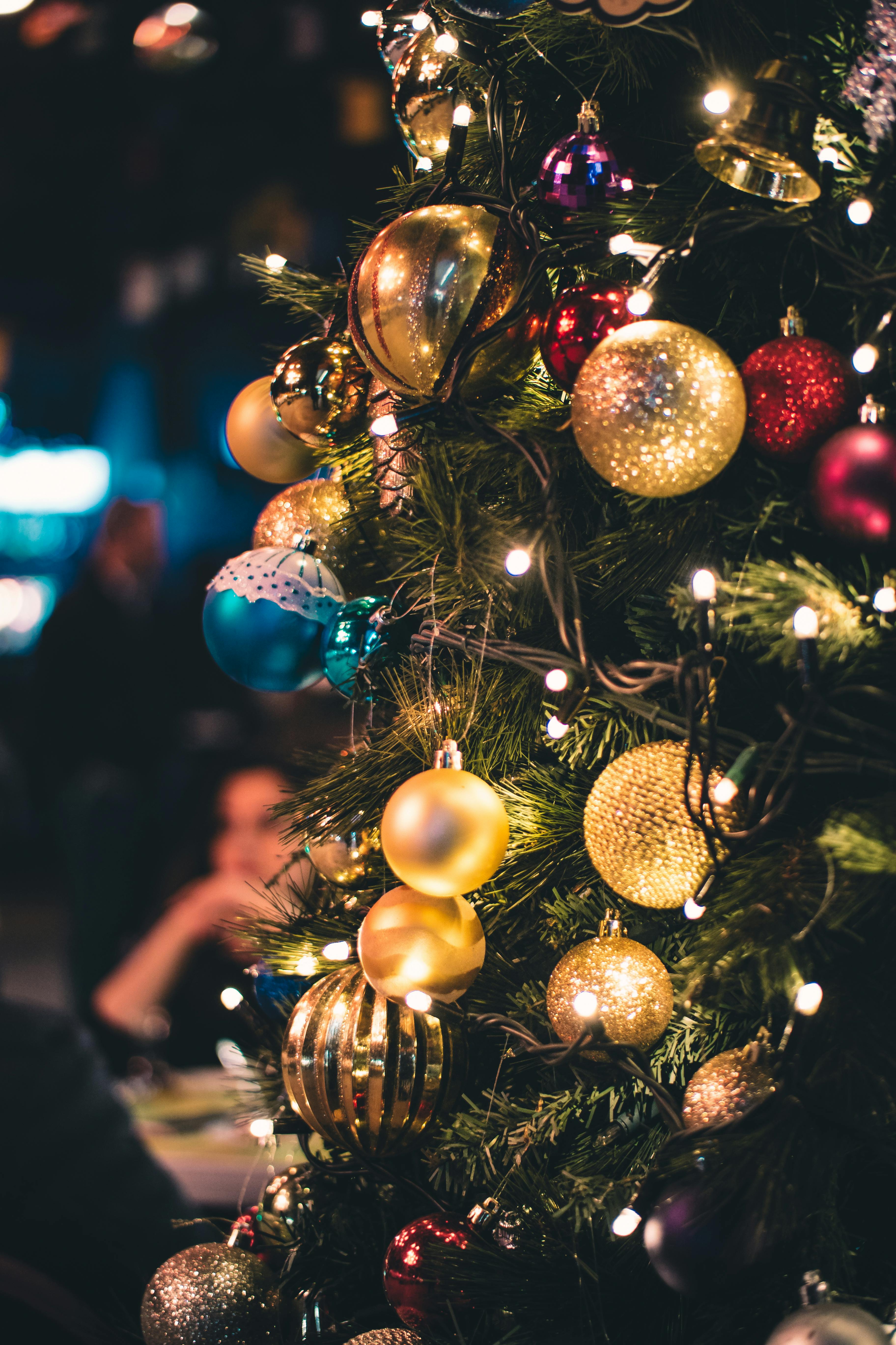 A close-up shot of a Christmas tree decorated with colorful baubles and twinkling lights. - wallpaper image