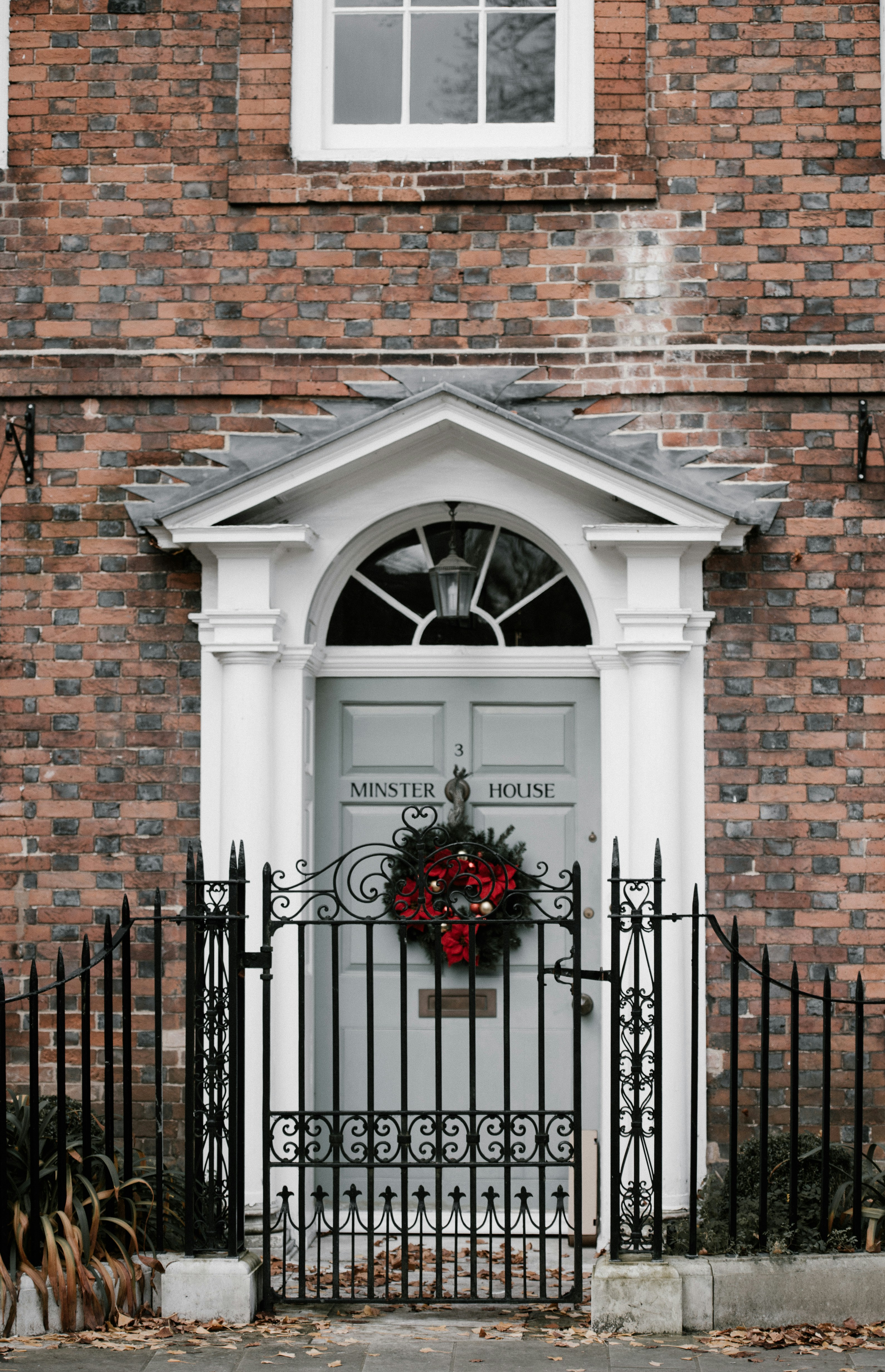 A red brick building with a red Christmas wreath hanging on the door, the door says "Minster House". - wallpaper image