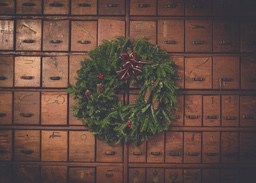 A Christmas wreath made of pine branches is decorated on a wooden drawer cabinet. - wallpaper image