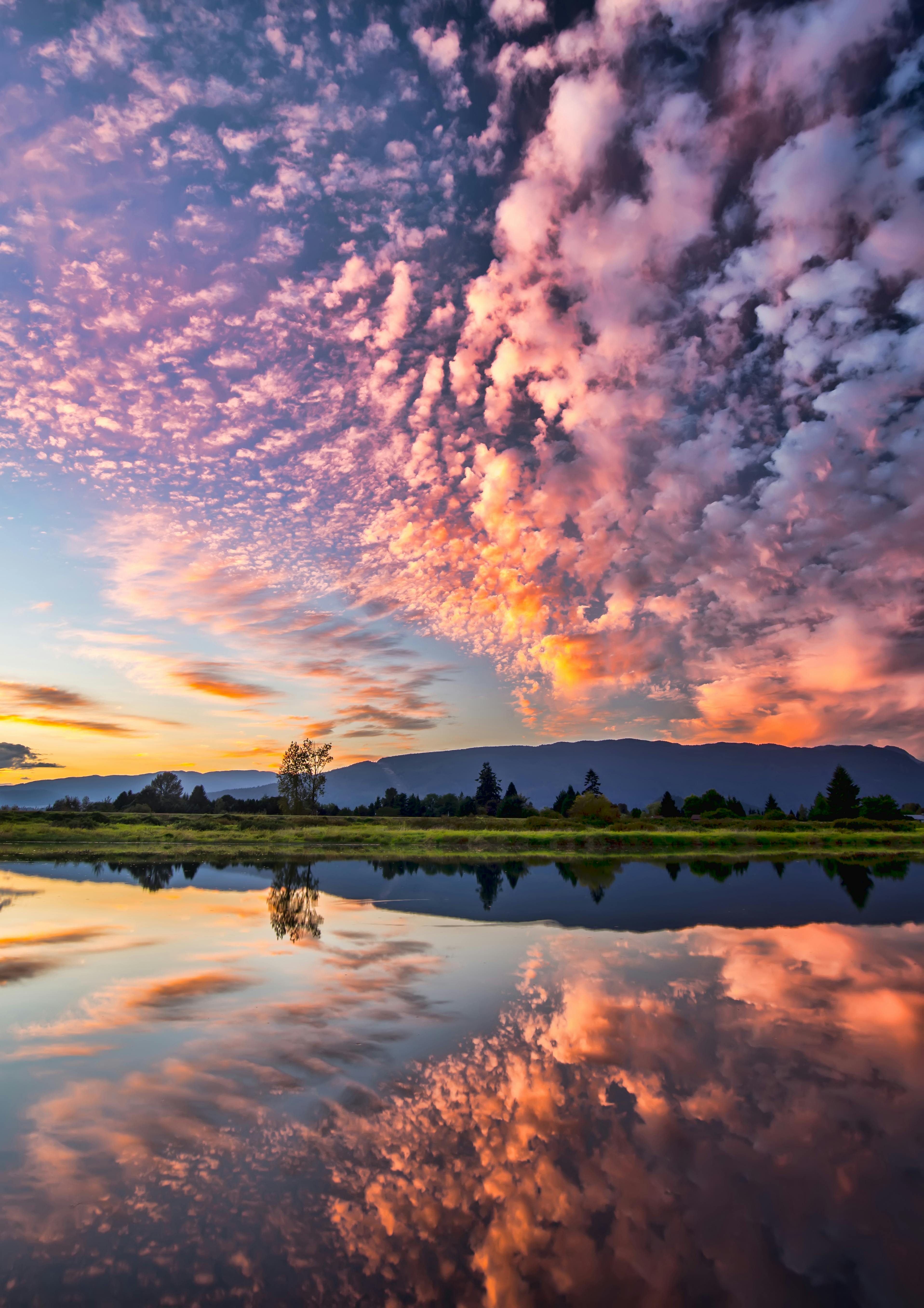 The sky is dotted with pink, purple and orange clouds at dawn, the clouds are reflected in the calm lake, forming a beautiful reflection. - free wallpaper image