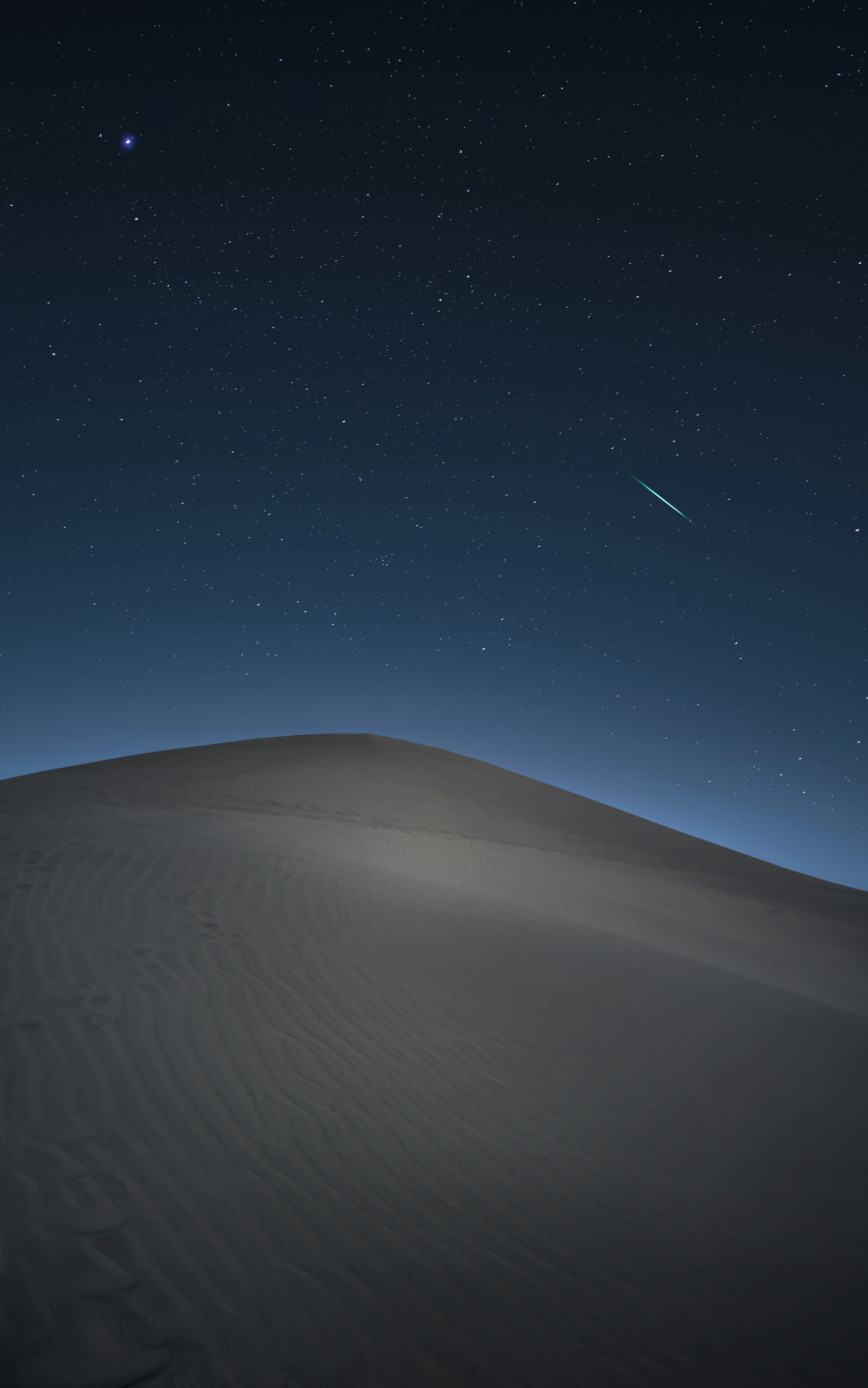 A starry night sky with a shooting star, a sand dune stands silently in the desert. - free wallpaper image