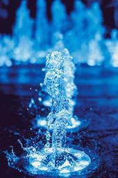 A fountain illuminated by blue light, water spurts from the center, forming water columns and splashes. - free wallpaper image