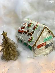 A gingerbread house decorated with Santa Claus, reindeer and snowman, next to a small golden Christmas tree. - wallpaper image