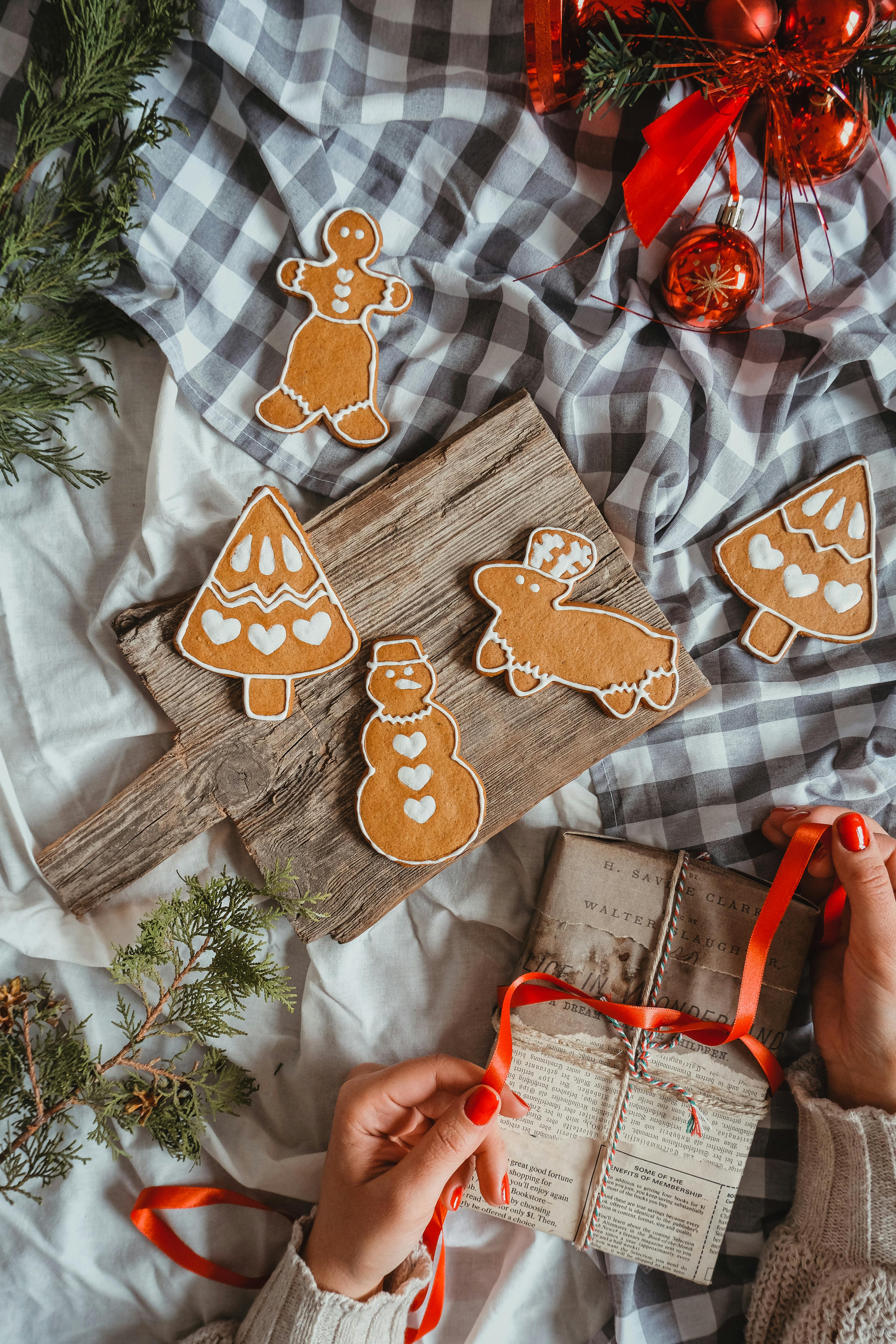 Christmas decorations, red ribbons, red balls, gingerbread men beside them and a wrapped gift. - wallpaper image