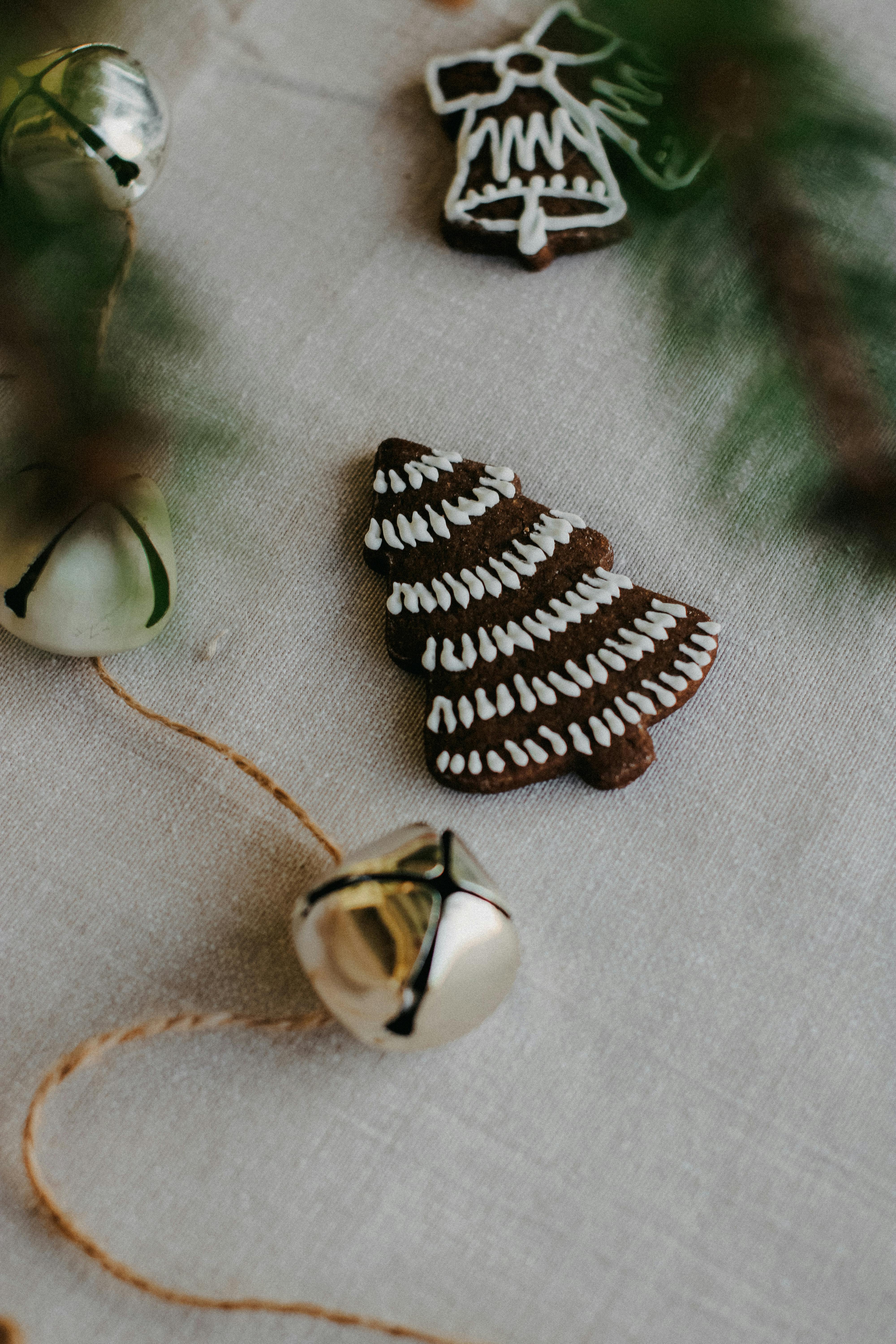 Some decorations are placed on a white tablecloth, the most prominent of which is a gingerbread man-shaped Christmas tree, with some silver bells next to it. - wallpaper image