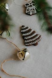 Some decorations are placed on a white tablecloth, the most prominent of which is a gingerbread man-shaped Christmas tree, with some silver bells next to it. - wallpaper image