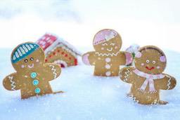 Three gingerbread men stand in the snow, one wearing a hat, one wearing earmuffs, and one wearing a hat and scarf. - wallpaper image