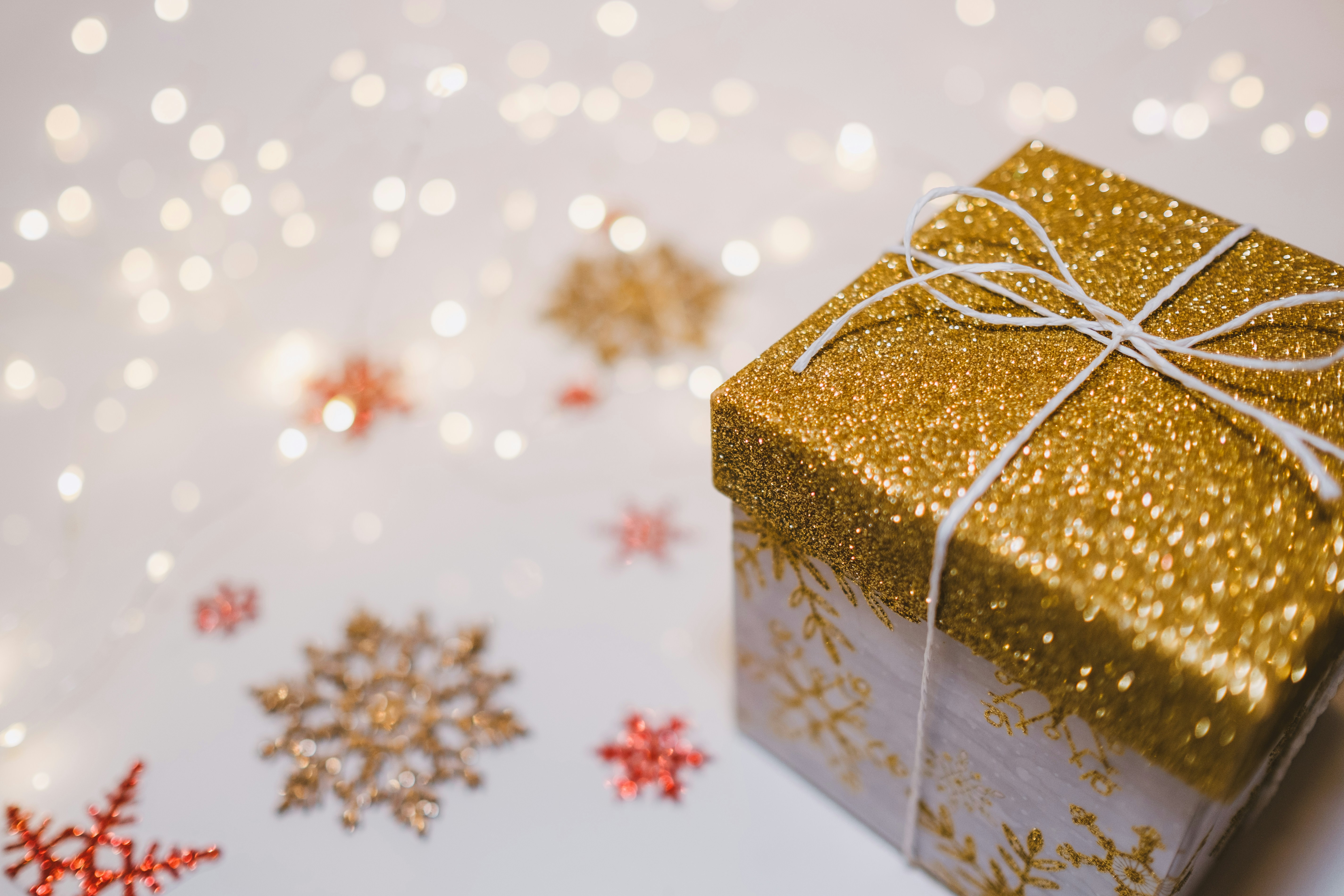 A golden gift box is placed on a white background, surrounded by red and gold snowflake decorations. - wallpaper image