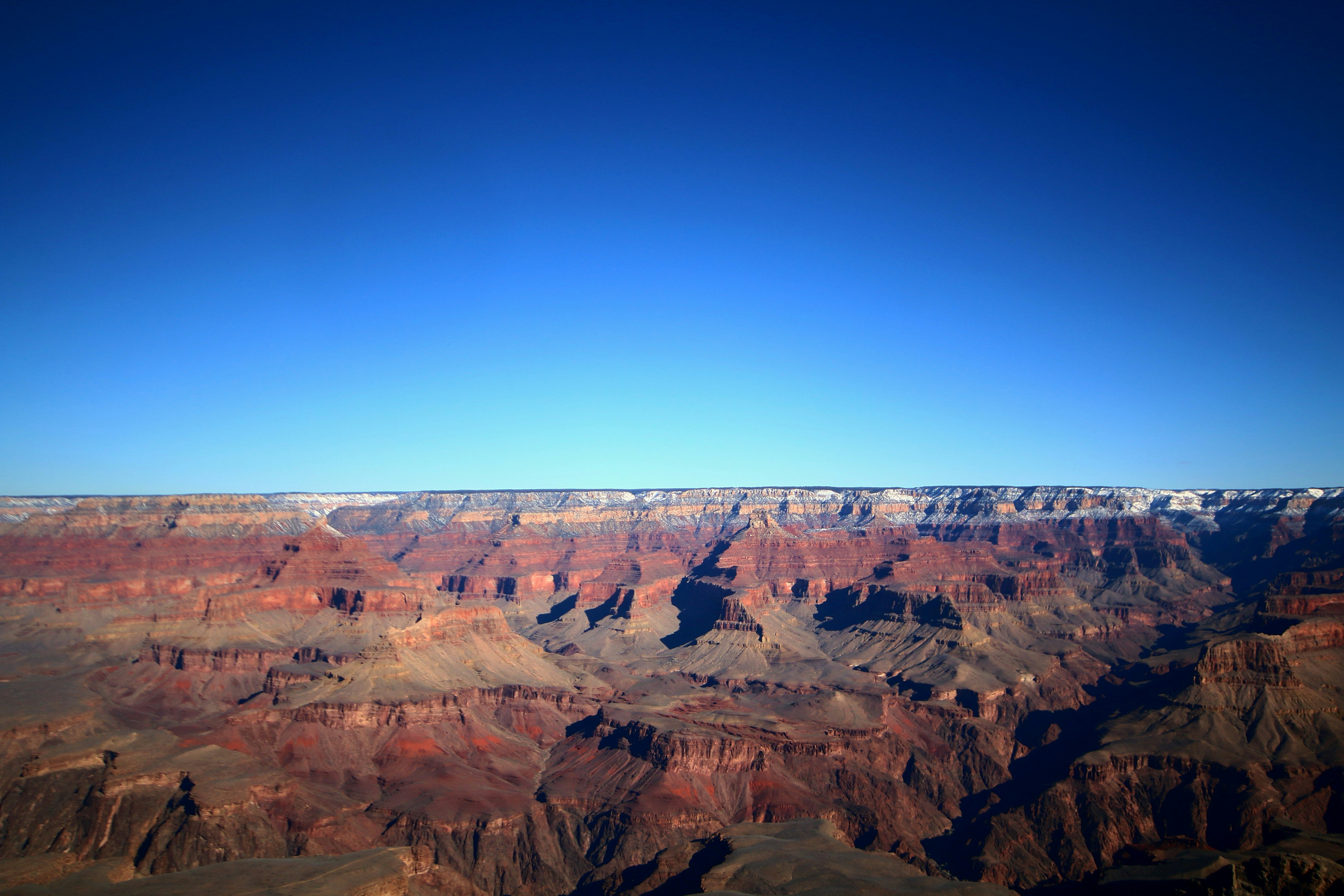 A view of the Grand Canyon, with red rock formations layered under a blue sky with white clouds. - free wallpaper image