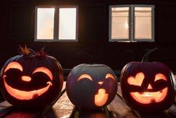 Three jack-o&apos;-lanterns are lined up on a wooden table, each with a different expression carved into them, with windows in the background and dim lighting. - wallpaper image