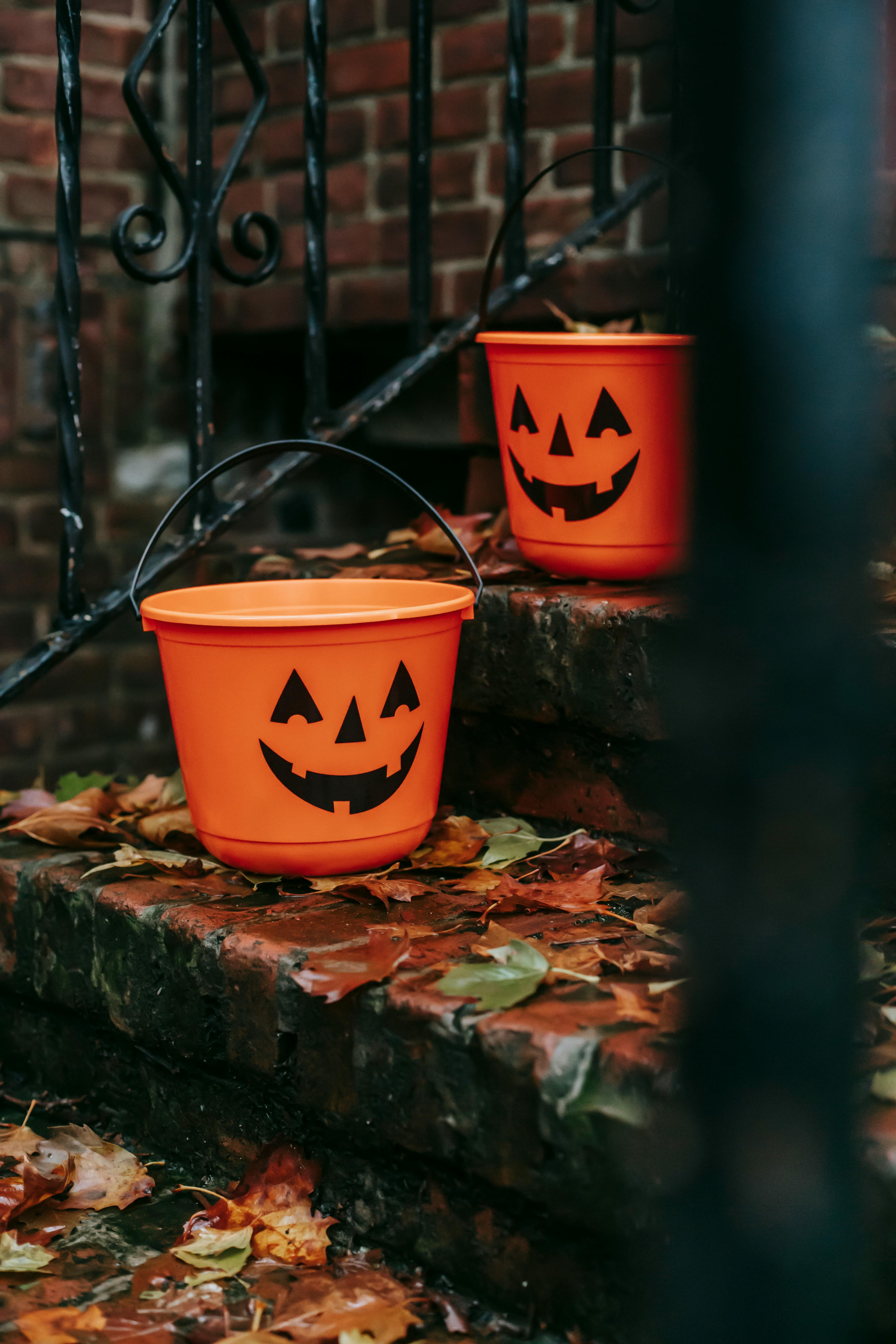 Two orange pumpkin buckets with pumpkin light patterns are on the steps, surrounded by fallen leaves. - wallpaper image