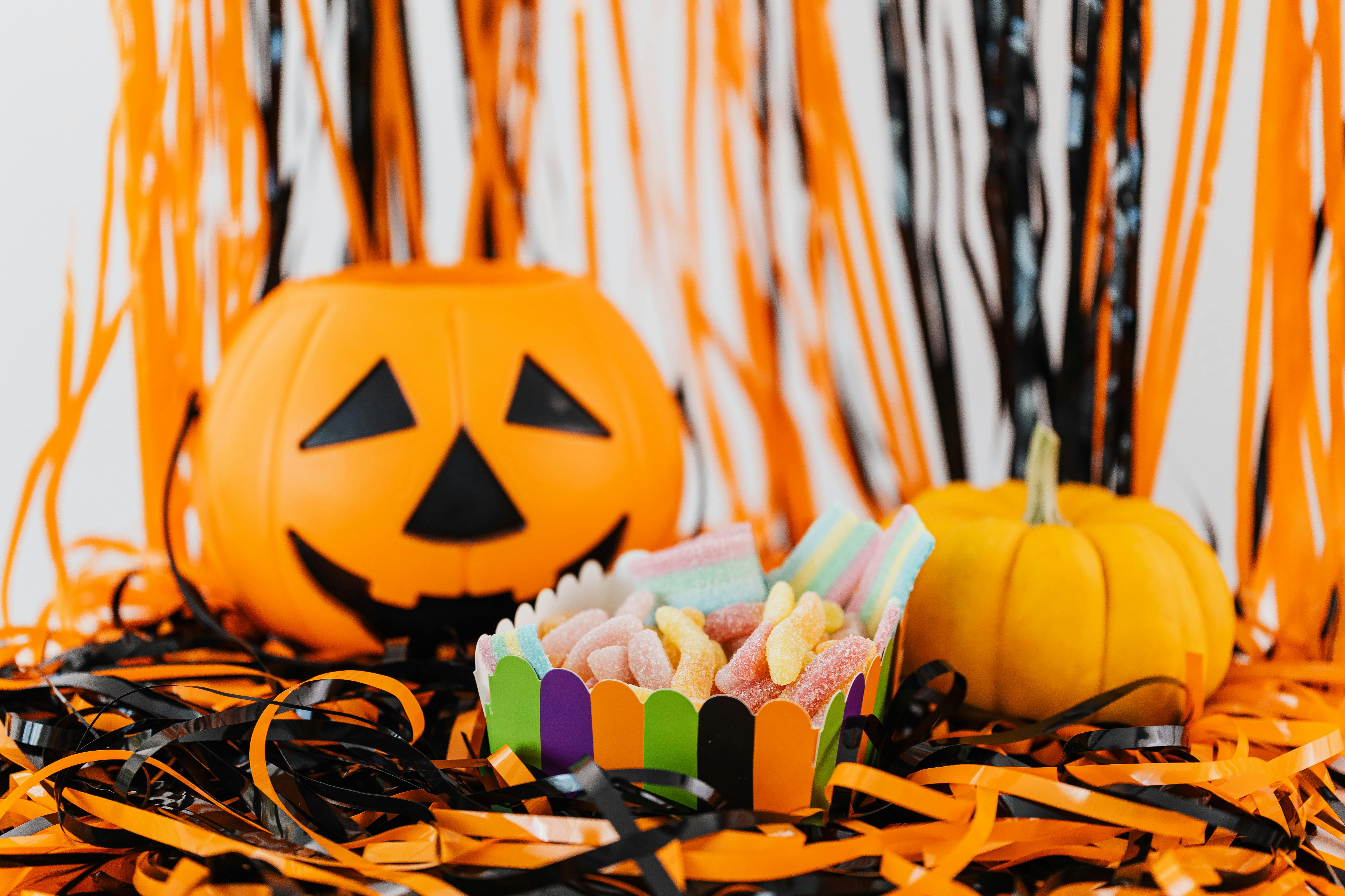 A jack-o'-lantern with a bowl of candy next to it, and a small pumpkin beside. - wallpaper image