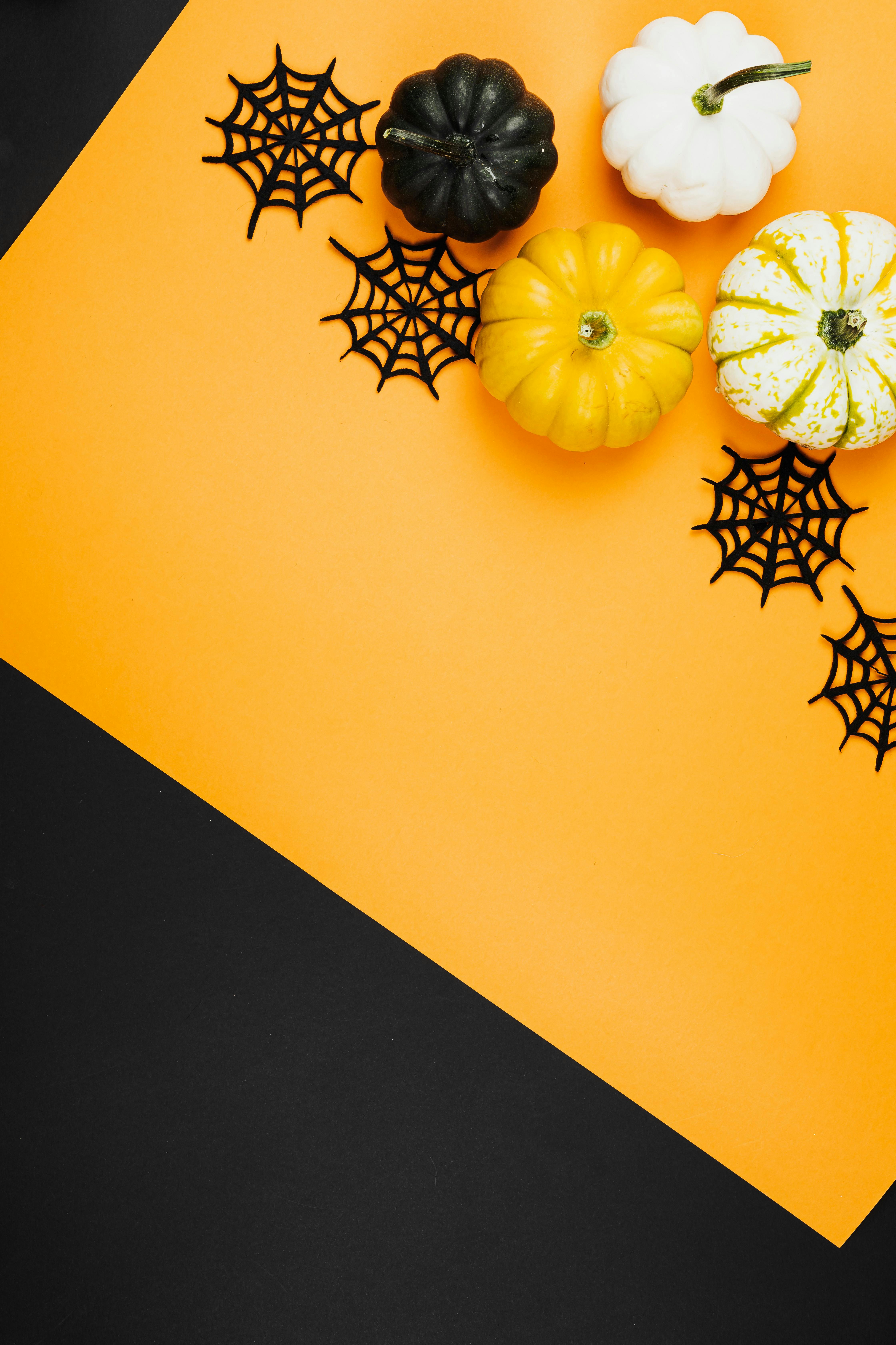 There are four pumpkins and some spiderweb decorations on an orange and black background. - wallpaper image