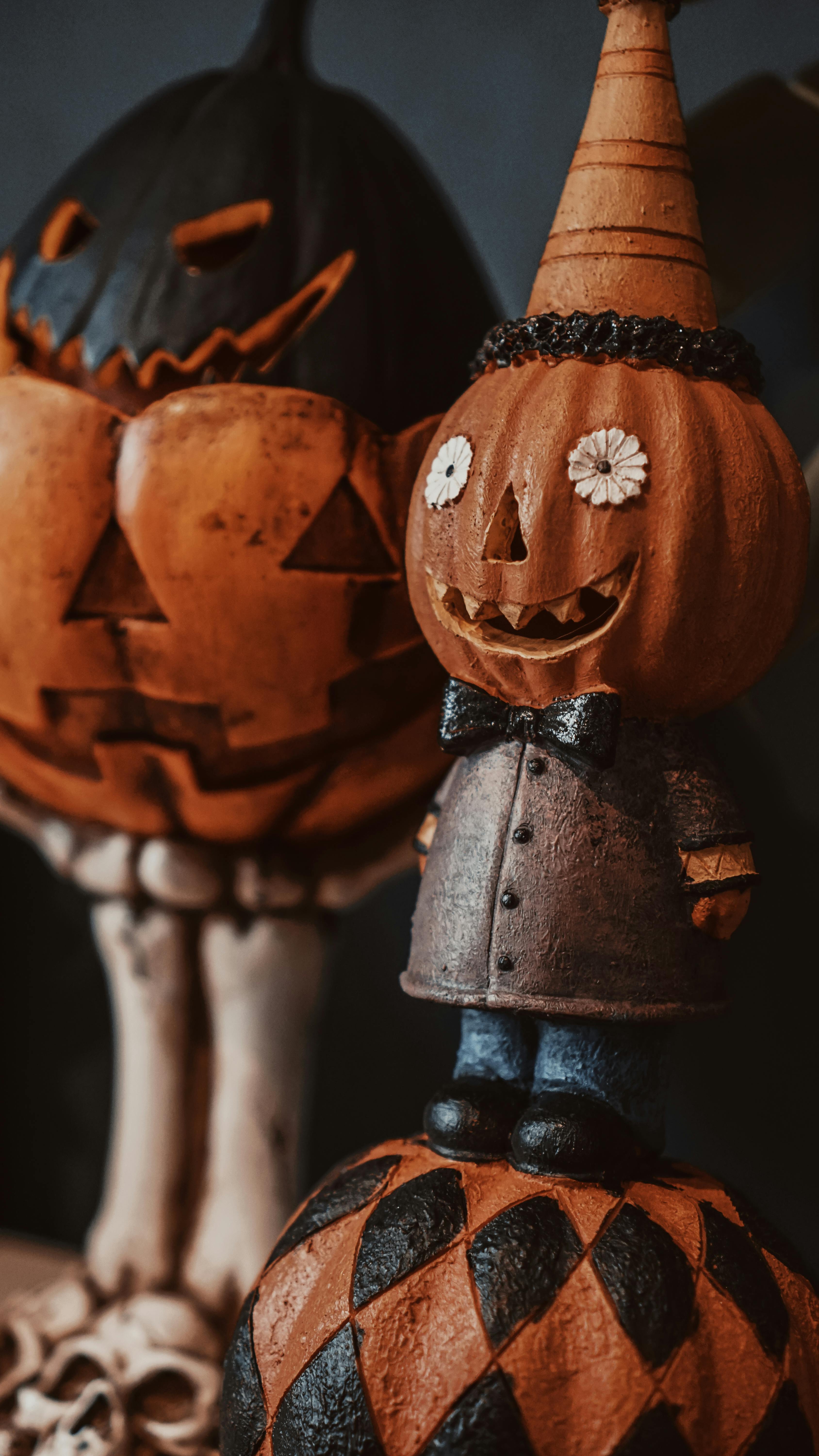 Two jack-o&apos;-lanterns, one wearing a hat and one without, stand on a pumpkin with black and white squares. - wallpaper image