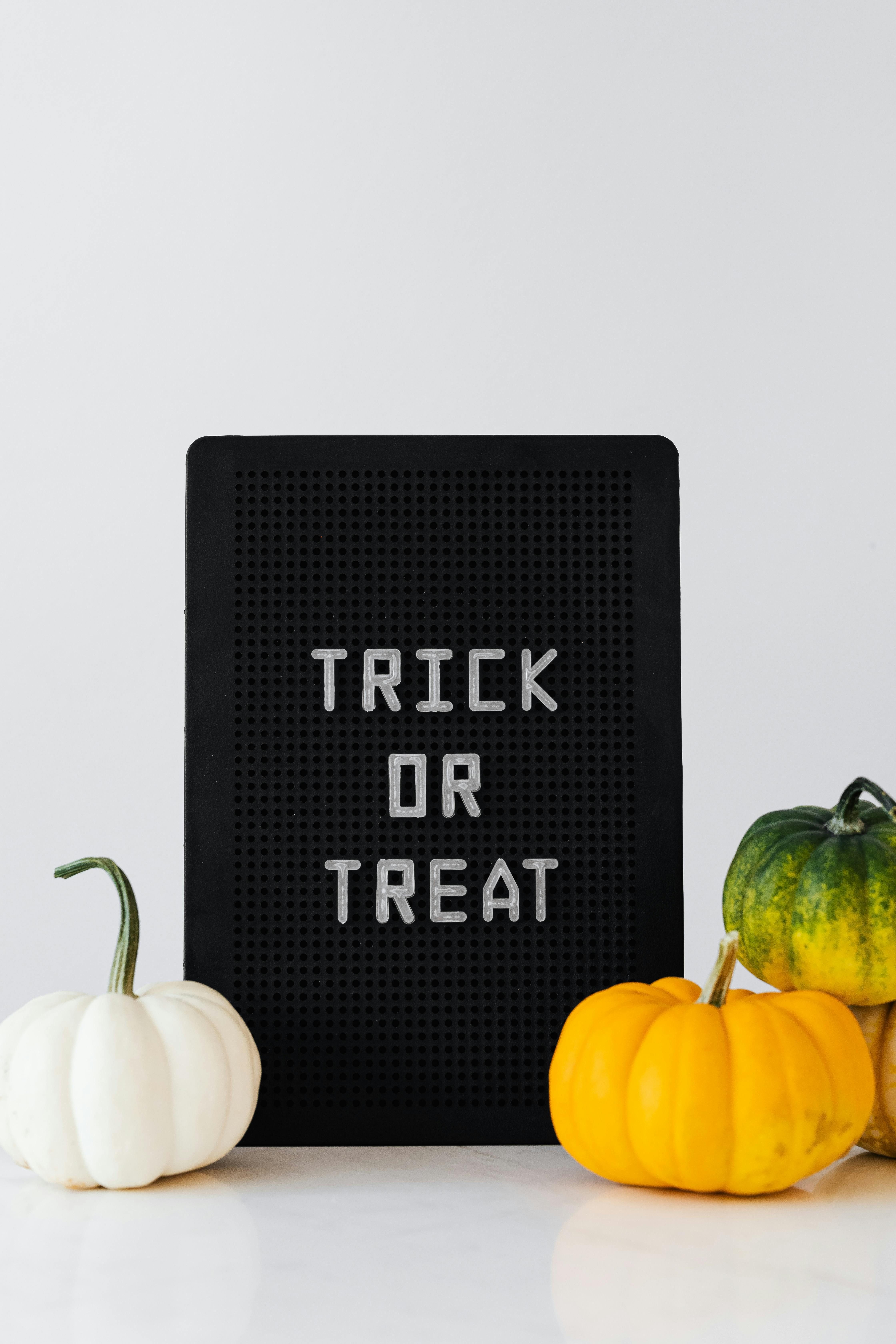 A black board with the words "trick or treat" written on it, with three pumpkins next to it. - wallpaper image