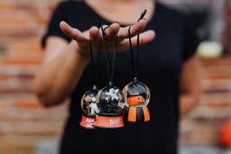 A hand is holding three Halloween themed snow globes, with a pumpkin, a ghost and a house inside. - wallpaper image