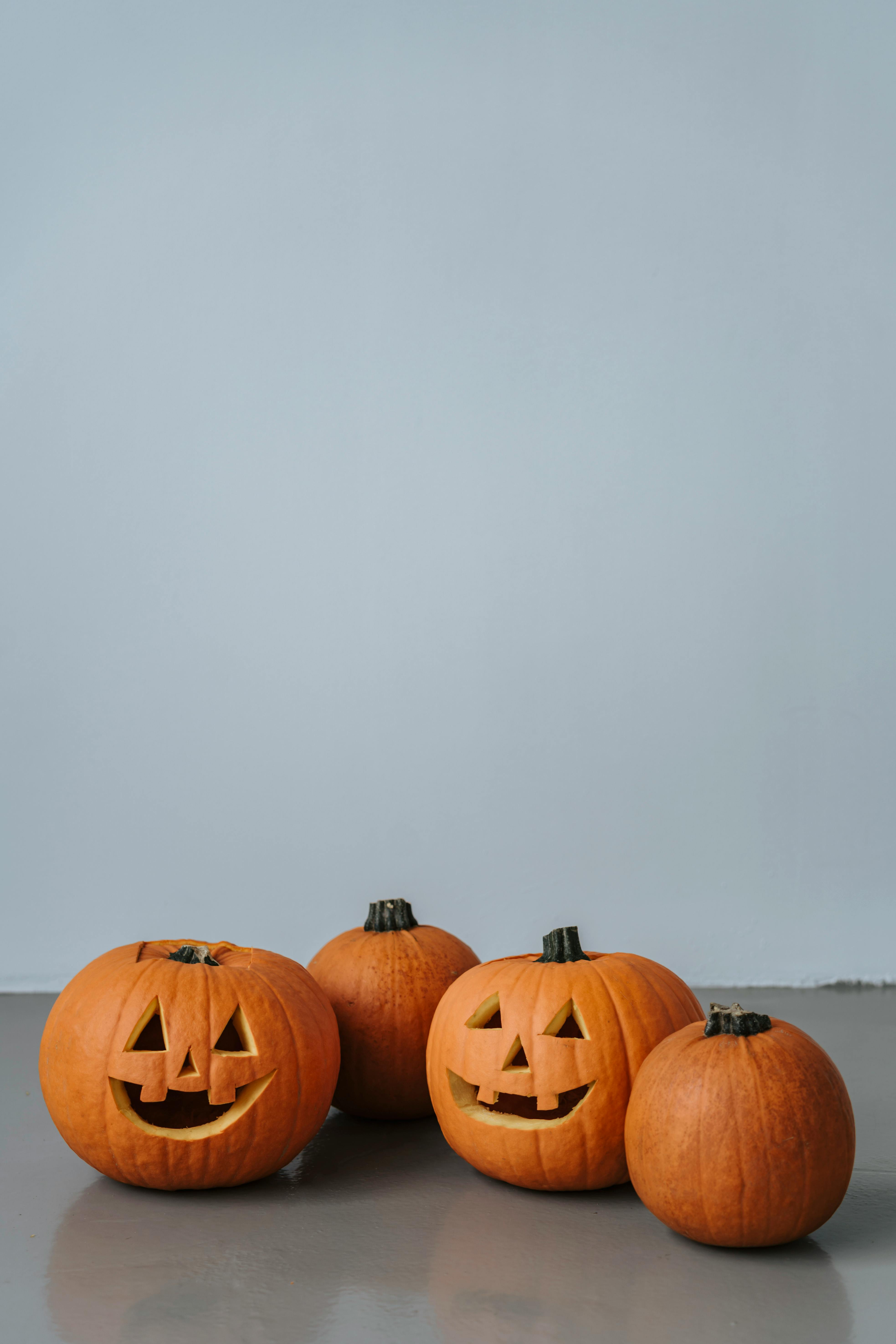 Four jack-o&apos;-lanterns, three of which are carved with smiling faces - wallpaper image