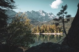 A mountain lake with clear water reflecting the blue sky, white clouds and distant snow-capped mountains. - free wallpaper image