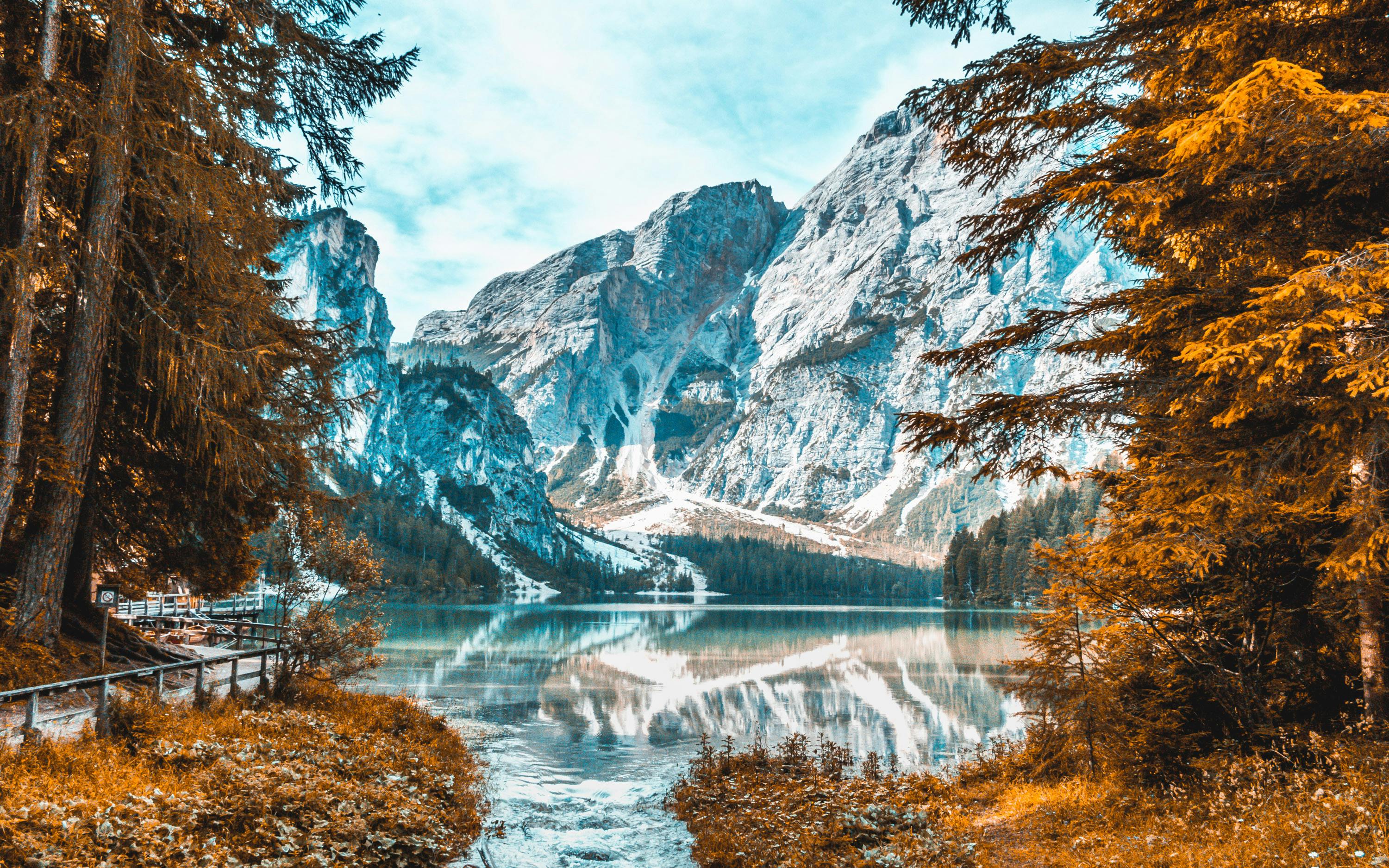 A mountain lake reflects the snow-capped mountains, the reflection of trees is clearly visible on the calm lake surface, the lake water is clear and transparent, the scenery is beautiful and peaceful. - free wallpaper image