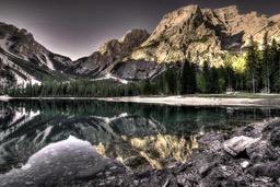 A calm lake surrounded by mountains, the water is clear and reflects the shadow of the mountain. - free wallpaper image