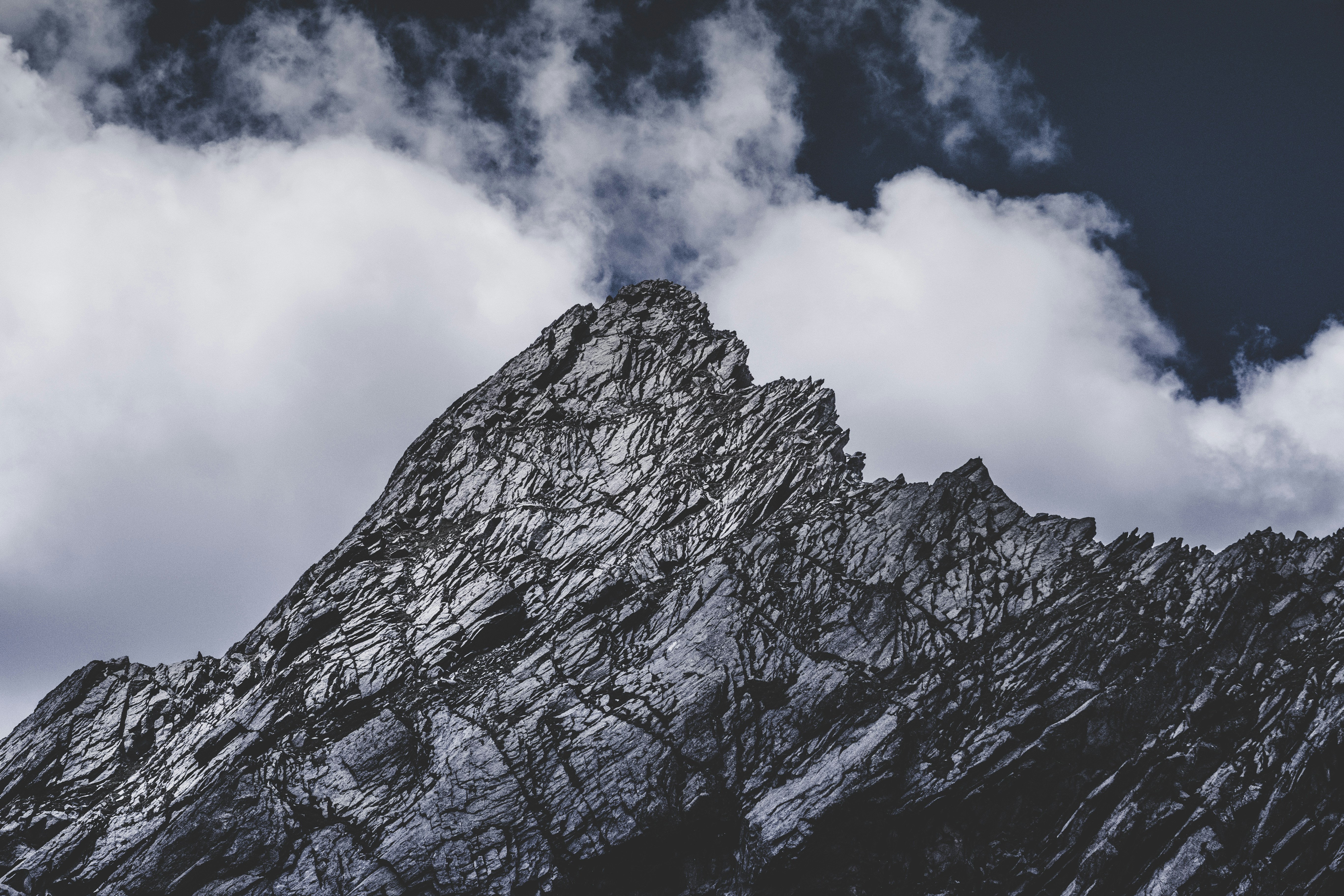 The top of the mountain is covered by clouds, the rock surface is grey and white - free wallpaper image