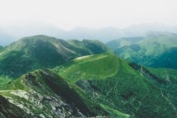 The distant mountains are shrouded in fog, the slopes are covered with lush greenery, it looks full of vitality. - free wallpaper image