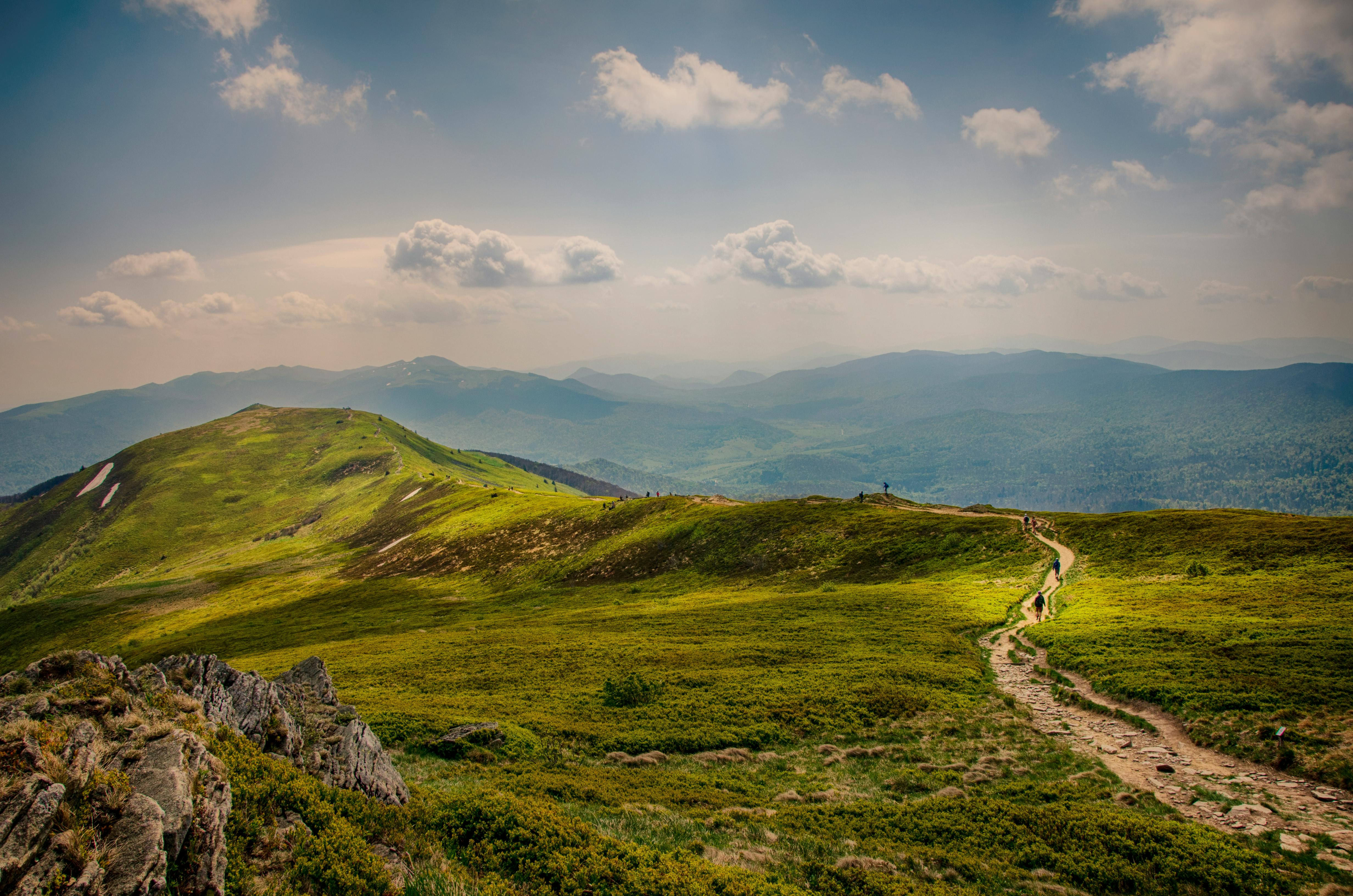 A winding path leads up to the mountain peak, overlooking the vast mountains in the distance. - free wallpaper image