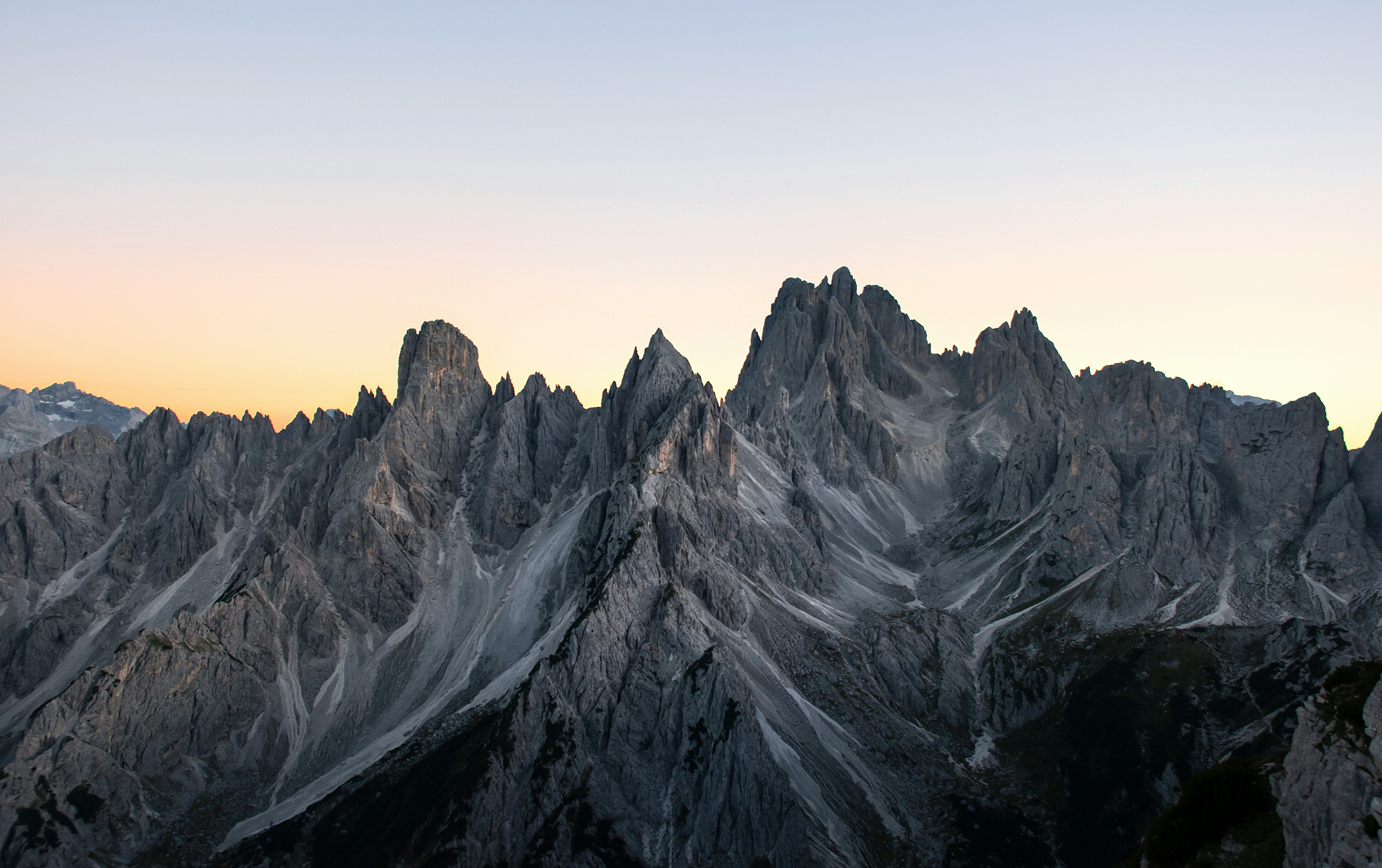 The mountain peaks are bathed in the warm glow of the setting sun, presenting a gray hue, the mountains have obvious textures, showing a magnificent view. - free wallpaper image