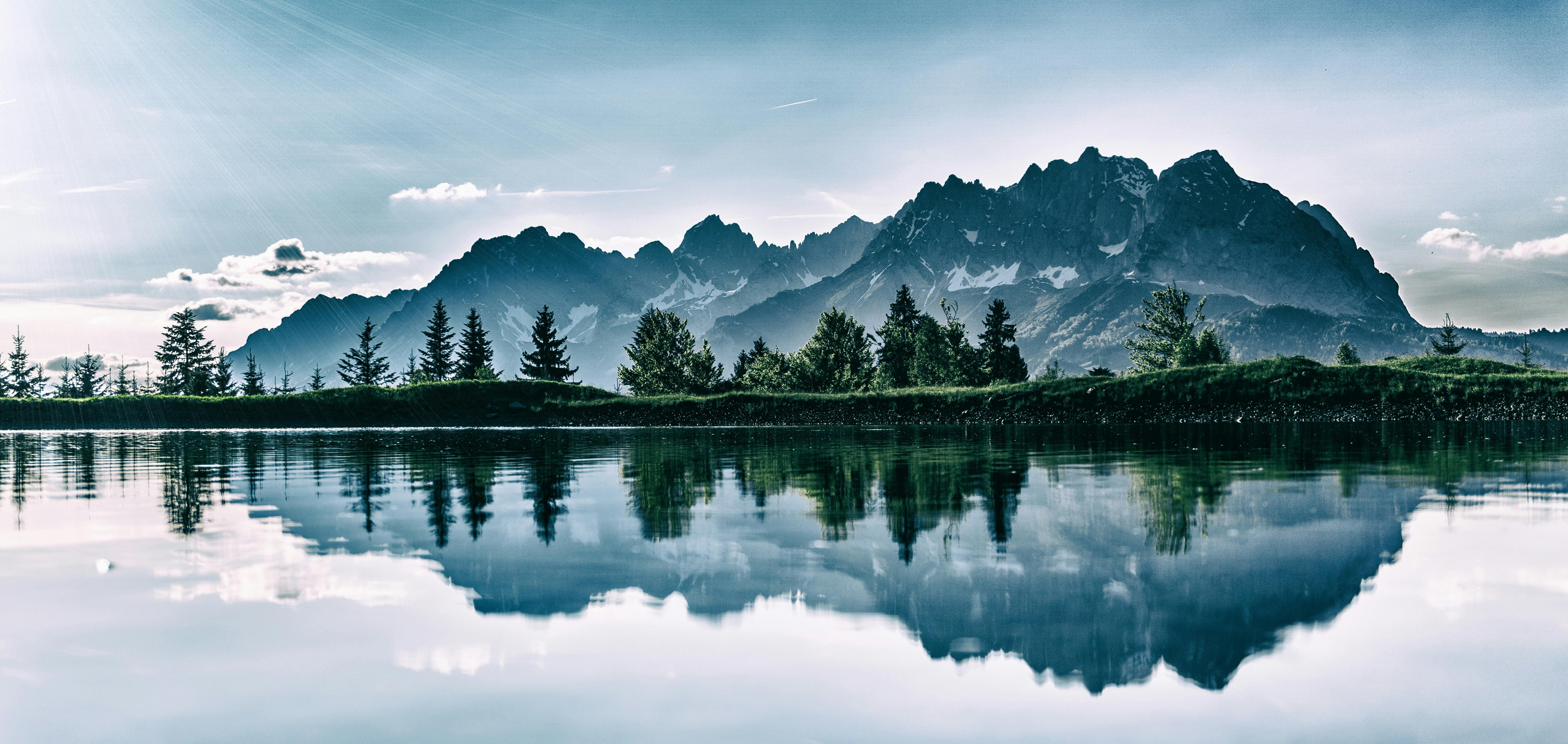 The mountain peaks are reflected in the calm lake water, forming a beautiful reflection. - free wallpaper image